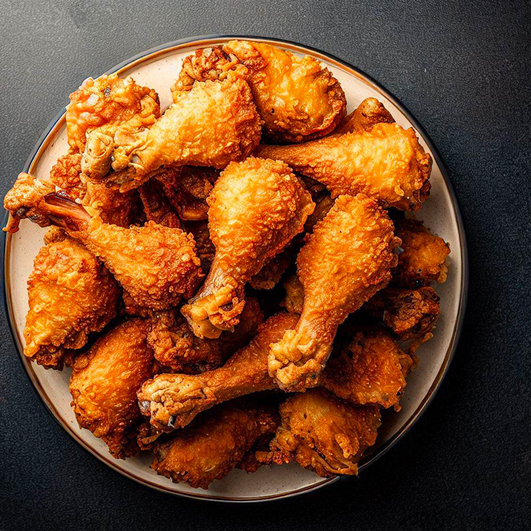 Overhead view of a plate filled with golden, crispy broasted chicken pieces.